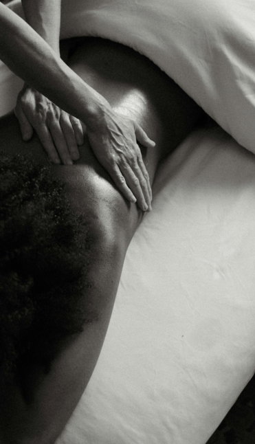 a-person-laying-on-a-bed-with-their-hands-on-their-back.jpg a person laying on a bed with their hands on their back